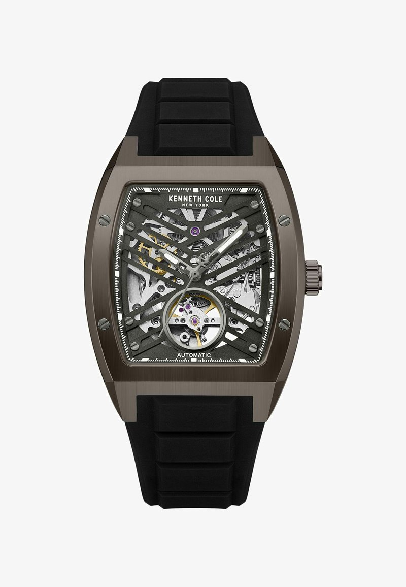 Automatische Armbanduhr mit einem schwarzen Gummiarmband, dunkelmetallischem Gehäuse, Skelettzifferblatt, das Zahnräder zeigt, silbernen Akzenten und lila Details.