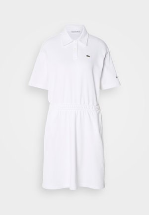 White polo dress made of soft fabric, featuring a collared neck, short sleeves, elastic waistband, and a small green logo on the chest.
