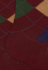 Calze al ginocchio con base rosso scuro, motivo a rombi lavorato a maglia nei colori verde, arancione e viola, con cuciture blu a contrasto.