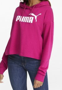 Sudadera corta magenta hecha de tela suave, con un gran logo blanco de Puma en la parte frontal y puños acanalados para un ajuste ceñido.