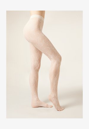 Benen met doorschijnende huidkleurige kousen van kant met een bloemenpatroon, staand met één voet plat op de grond en de andere licht op de tenen.