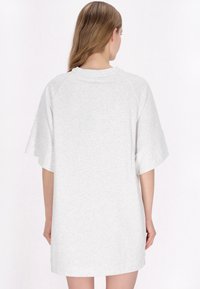 Jasnoszara, w oversize'owym stylu sukienka t-shirtowa, wykonana z miękkiego materiału, z krótkimi, szerokimi rękawami i prostym okrągłym dekoltem. Brak widocznych wzorów lub akcentów.