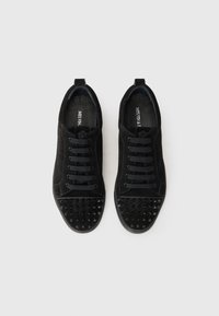 Black suede sneakers with lace-up design, textured studded toe cap, rubber outsole, and flat laces. Classic silhouette and minimalist style.