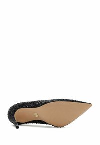 Chaussure à talon haut à bout pointu avec une tige noire texturée, ornée de strass et dotée d'une semelle beige lisse.