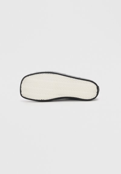 Shoe sole with black edge and white herringbone textured tread, displayed flat on a plain white background.
