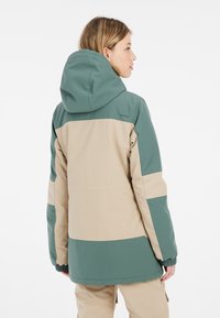 Mehrfarbige Jacke mit einem grünen und beigen Design, gefertigt aus einem glatten, strapazierfähigen Material, mit Kapuze, elastischen Bündchen und Seitentaschen.