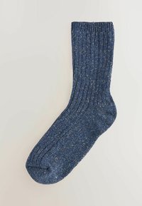 Blå prickig socka med ribbstruktur, rund tå och förstärkt häl. Tillverkad av ett mjukt, varmt material som passar för avslappnad användning.