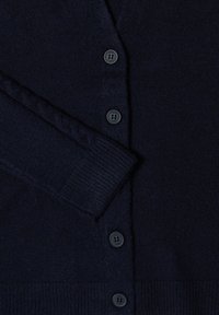 Marinblå cardigan i mjukt, texturerat tyg med knäppning fram, ribbade ärmslut och nederkant. Har två runda knappar med fyra hål vardera.