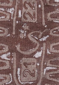 Brown knitted fabric featuring embossed numbers and symbols, partially covered with white snow, showcasing a textured and layered design.