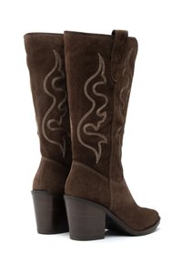 Botas de ante marrón hasta la rodilla con un diseño bordado curvado en hilo claro, que presentan un tacón apilado y un acabado texturizado.