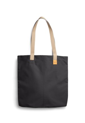 Sac fourre-tout noir avec des anses d'épaule beiges et une petite étiquette de marque orange sur le côté supérieur droit, sur fond blanc.