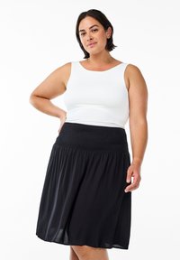 Jupe noire, mi-longue, avec une ceinture froncée, associée à un débardeur blanc ajusté. Tissu lisse avec un tombé doux.