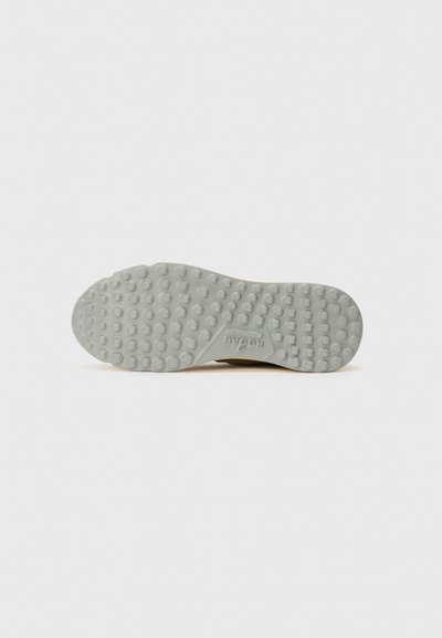 Sole of a light gray shoe with raised circular grips and "HOGAN" branding embossed near the arch area.