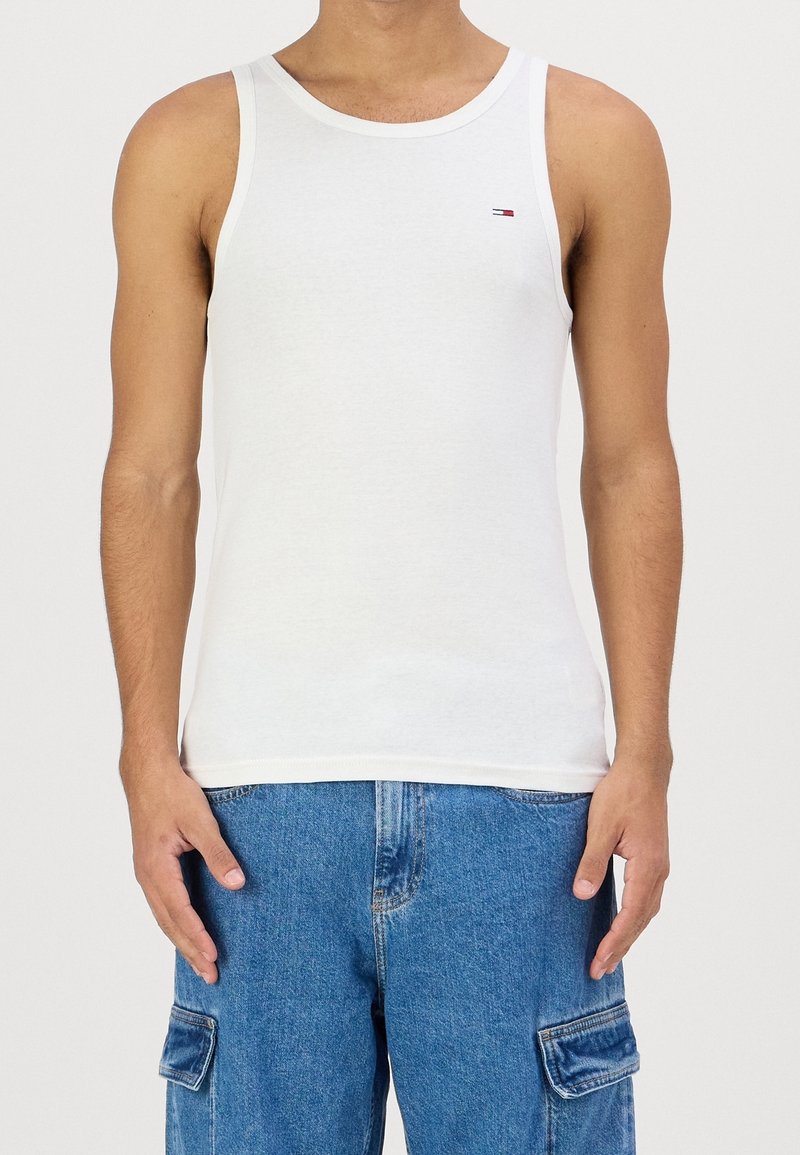 Top sin mangas de algodón blanco con escote redondeado y tirantes delgados, que presenta un pequeño logo en el lado izquierdo del pecho.