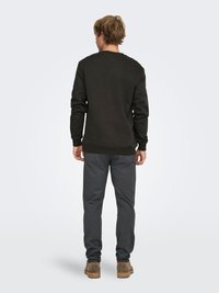 Mørkegrøn sweatshirt med rund hals, kombineret med grå bukser. Blødt stof, afslappet pasform og ribbede ærmegab. Afslappet fodtøj fuldender looket.