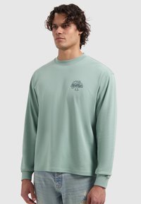 Mintgroene lange mouw shirt met een ronde hals, voorzien van een klein grafisch logo op de linkerborst en een zachte, gladde stofstructuur.