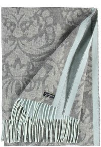 Couverture grise tissée avec un motif damassé subtil, finie avec une frange et une bordure vert menthe. Étiquette de marque visible dans le coin inférieur.