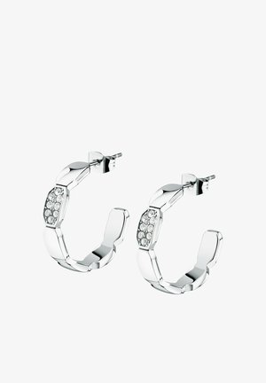 Boucles d'oreilles créoles en argent avec un design en chaînes reliées, ornées de cristaux clairs sur un côté et une finition polie. La forme est circulaire avec une texture épaisse.