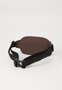 Καφέ νάιλον τσάντα μέσης με λεία υφή, διαθέτει μαύρο προσαρμόσιμο λουράκι και πλαστικό κούμπωμα. Συμπαγής και οβάλ σχεδίαση.