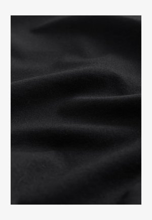 Černá bavlněná látka s hladkou strukturou, s jemnými záhyby a vráskami, které zdůrazňují její lehkost a pružnost.