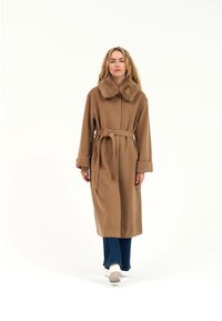 Langer brauner Mantel mit einem Pelzkragen, tailliert mit Gürtel und weiten Ärmeln. Das Material wirkt weich, mit einer glatten Textur und ohne sichtbare Muster.