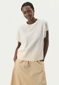 Lys beige stribet striktrøje med kortærmer og ribbet afslutning. Sammen med en lysebrun nederdel, der har sidelommer.