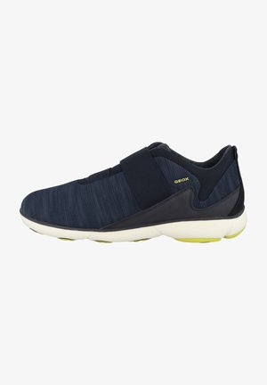 Zapatilla navy con parte superior de textil y cinta de velcro, suave acolchado y suela blanca duradera con acentos verdes.