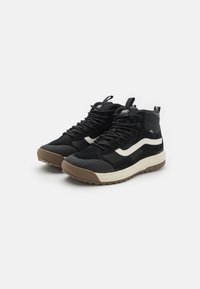Zapatillas altas negras de mezcla de ante y materiales textiles, con una franja lateral blanca y una suela de goma marrón texturizada.