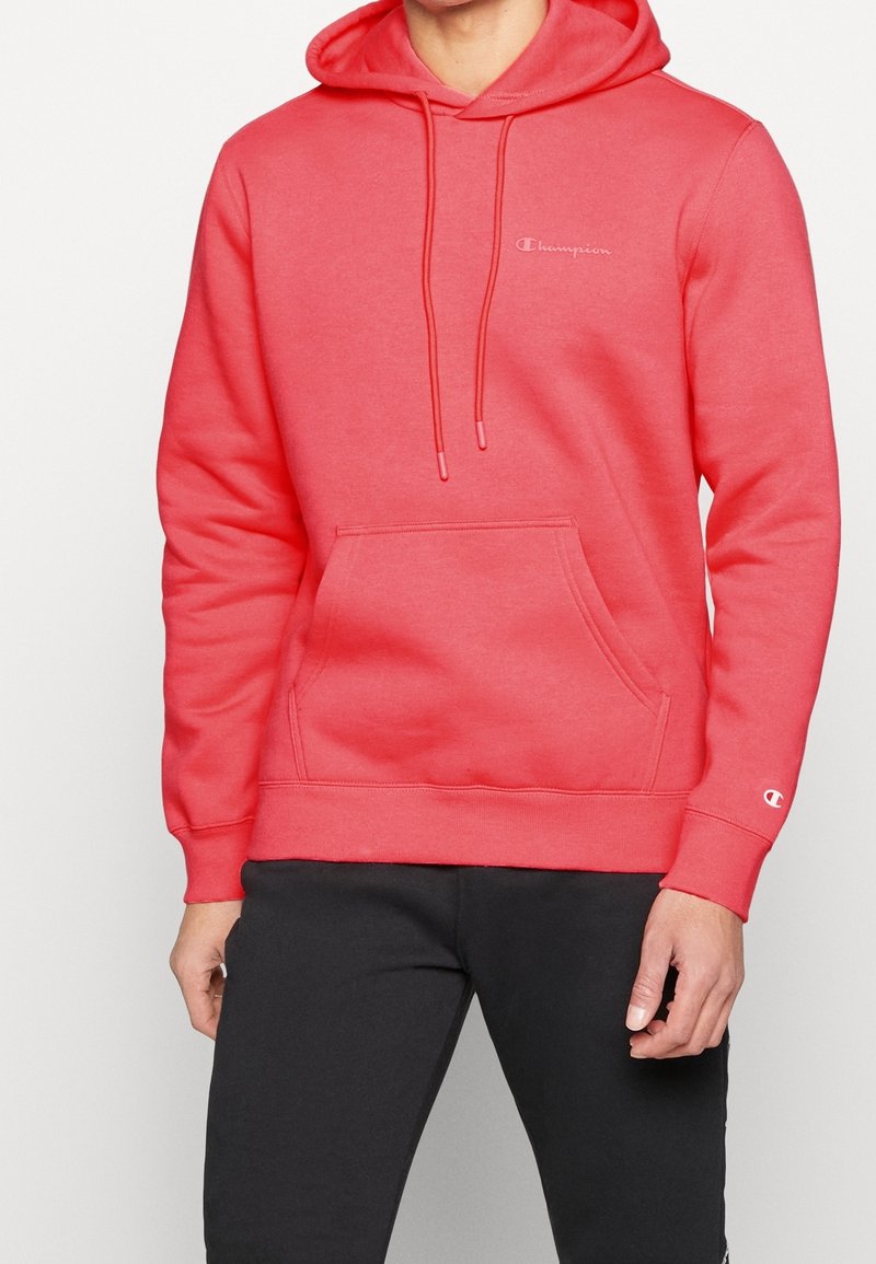 Sudadera color coral con un bolsillo frontal, capucha con cordón y logotipo bordado. Tejido suave con puños y dobladillo acanalados.
