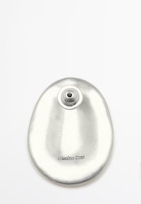 Fibbia metallica argentata con forma ovale, superficie liscia e un fermaglio centrale per il fissaggio. Presenta la marchiatura incisa "Massimo Dutti".