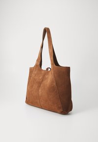 Sac fourre-tout en daim marron avec deux poignées, présentant une texture lisse et un design minimaliste avec des coutures courbes et sans quincaillerie visible.