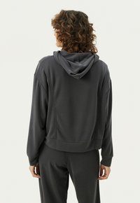 Hallide hallitusseenedadega hall cropped-hoodie, pehme tekstuuriga, pikad varrukad ja soonikkoes mansetid. Kombineeritud sobivate hallide pükstega.