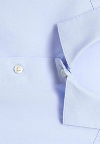 Camicia button-up azzurro chiaro con una texture liscia, colletto a punta e un singolo bottone bianco al collo, caratterizzata da cuciture ben rifinite.