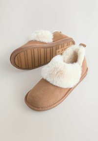 Pair of tan slip-on slippers with white fluffy lining and rubber soles, positioned on a light background.