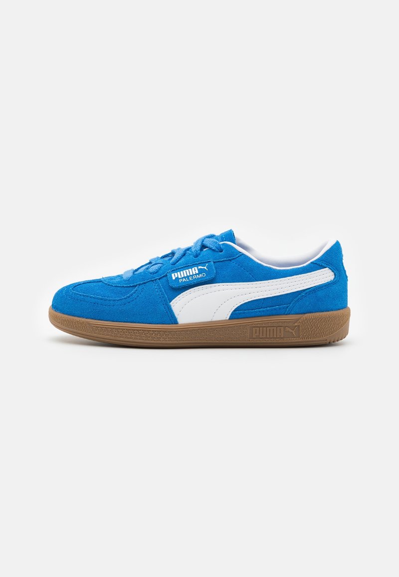 Baskets en suede bleu avec des accents blancs, semelle en caoutchouc et bout arrondi. Présente un design courbé et une étiquette avec le logo Puma sur le côté.