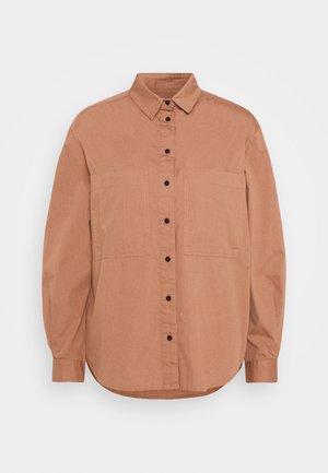 Rust-colored shirt made of a soft fabric, featuring a collared neck, full-length sleeves, buttoned front, and two chest pockets.