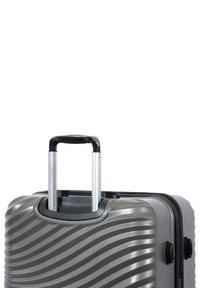 Hard-shell suitcase in metallic gray with wavy texture, retractable black handle, and zipper closure; features dual wheels for mobility.