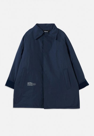 Navy blue coat in a lightweight, water-resistant fabric with a curved collar, side pockets, and white text detailing on the left side.