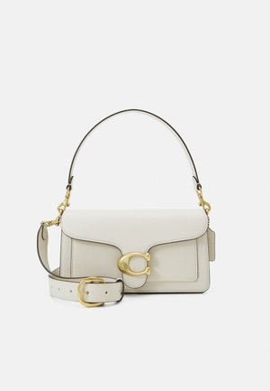 Bolso de cuero blanco con herrajes dorados, con cierre de solapa y una correa desmontable y ajustable. Adorno metálico redondeado en el centro.