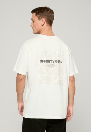 Weißes Baumwoll-T-Shirt mit einem quadratischen Grafikdesign auf der Rückseite, auf dem "OFF DUTY GEAR" steht, hellbeiger Hintergrund und abstraktes Linienmuster.