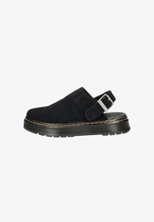 Sabots en daim noir avec un orteil large et arrondi et une sangle ajustable. Présente une semelle en caoutchouc noir texturé avec des accents de couture jaune.