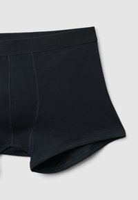 Boxer da uomo neri con un design semplice e cuciture a macchina, disposti piatti su uno sfondo grigio chiaro.