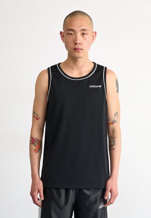 Canotta sportiva nera senza maniche realizzata in tessuto mesh testurizzato, con bordi bianchi e piccolo logo Adidas sul petto. Indossata con pantaloni corti neri.