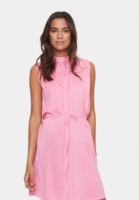Vestido rosa sin mangas con un escote alto, cintura ajustada con lazo y un corte relajado, fabricado con una tela ligera de textura suave.