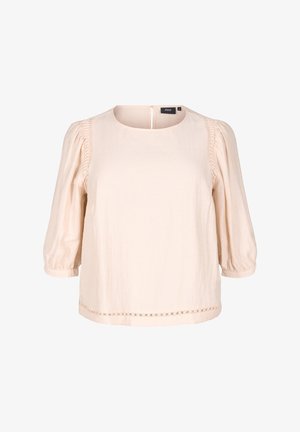 Šviesiai smėlinė bliuzonė su apvalia iškirpte ir trimis ketvirtadaliais pūstomis rankovėmis. Pasižymi klostėmis šonuose ir dekoratyviniu apvadu apačioje.