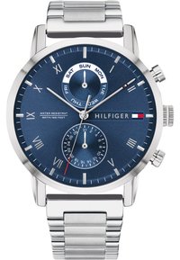 Montre en acier inoxydable argenté avec un cadran bleu marine. Les caractéristiques incluent un sous-cadran de date, des indicateurs de jour et un bracelet métallique lisse.