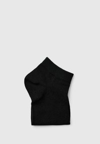 Calcetín negro de tobillo, textura acanalada, con punta redondeada y puño elástico para un ajuste seguro, exhibido sobre un fondo claro y liso.