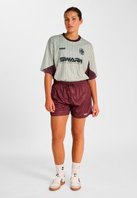 Sportliches Outfit mit einem hellgrün gestreiften Kurzarmhemd und bordeauxroten Shorts aus atmungsaktivem Stoff, mit tailliertem Schnitt und Logodetails.