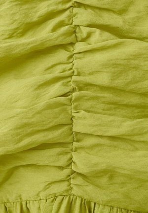 Tessuto verde brillante con strette pieghe verticali che creano pieghe arricciate e strutturate lungo il centro.