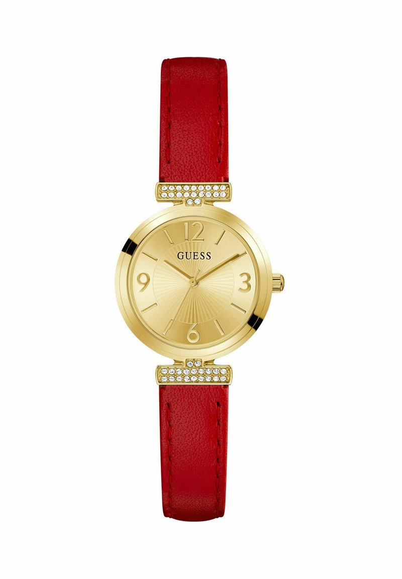 Reloj dorado con una esfera texturizada, correa de cuero rojo y herrajes con cristales en los soportes. Presenta marcadores de hora en negrita.